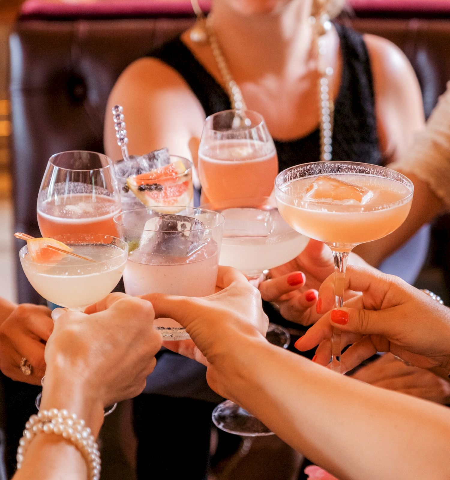 A group of people holding glasses with various drinks, seemingly celebrating or toasting together in a social setting.