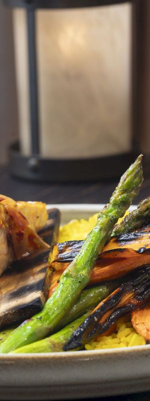 A plated meal consisting of salmon, grilled vegetables, yellow rice, and a glass of white wine on the side ends the sentence.